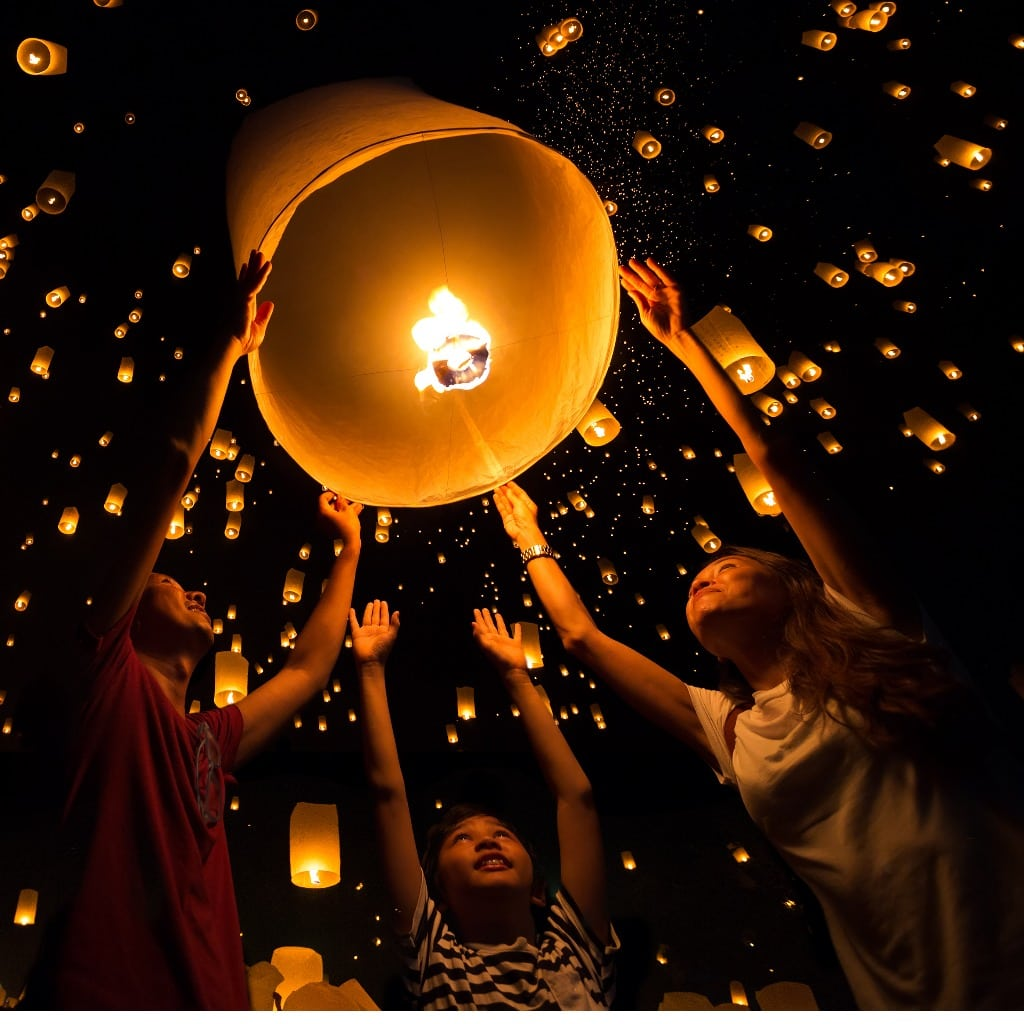 A group of youngers raising a hot air lantern into the sky, amidst a million other lanterns