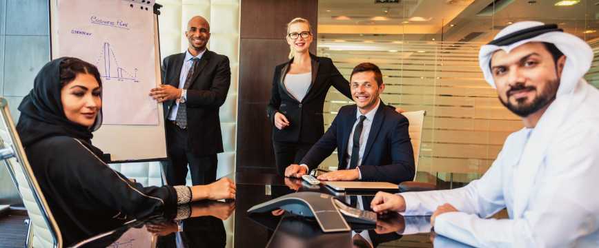 Grupo multicultural de profesionales reunidos en una sala de juntas moderna durante una reunión de negocios internacional