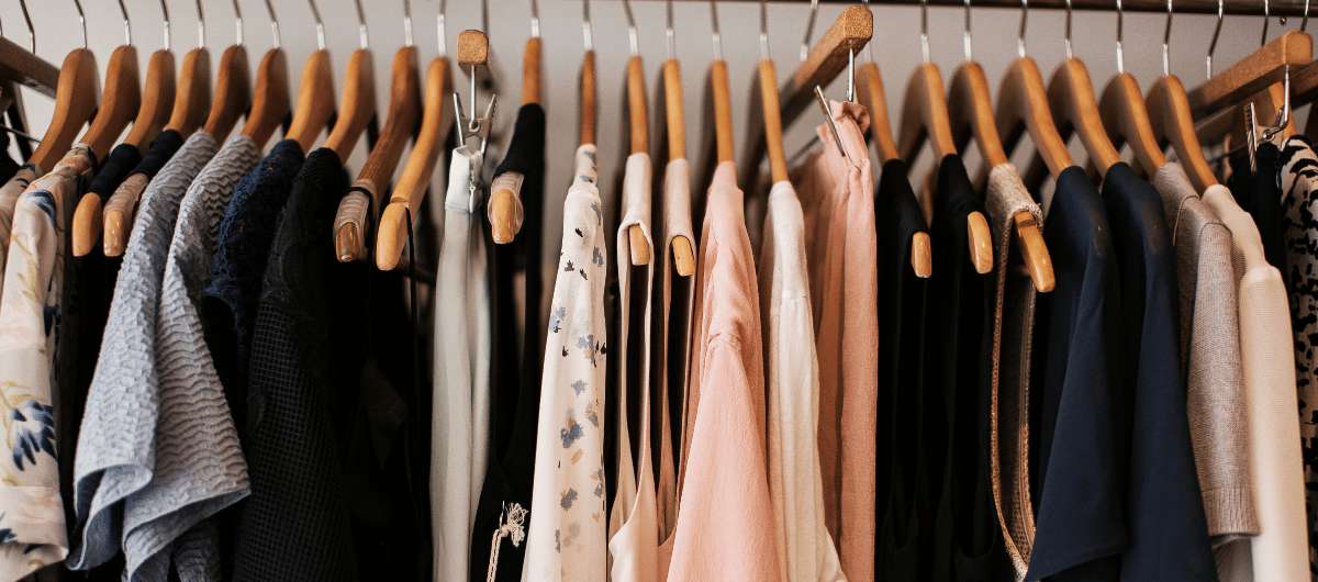 Perchero con variedad de prendas de vestir colgadas, camisas y blusas de distintos colores