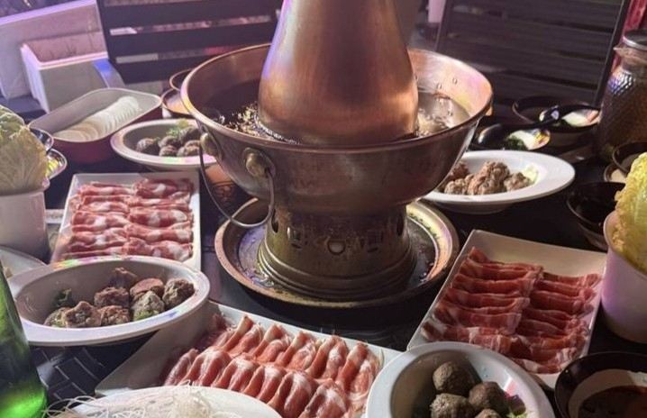Beijing-style hot pot with sliced meat, vegetables, and dipping ingredients