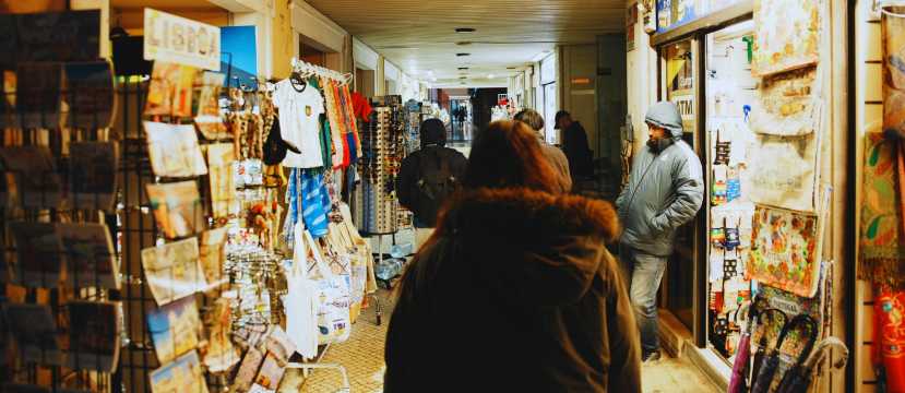 Pasillo de mercado cubierto con puestos de souvenirs y personas caminando