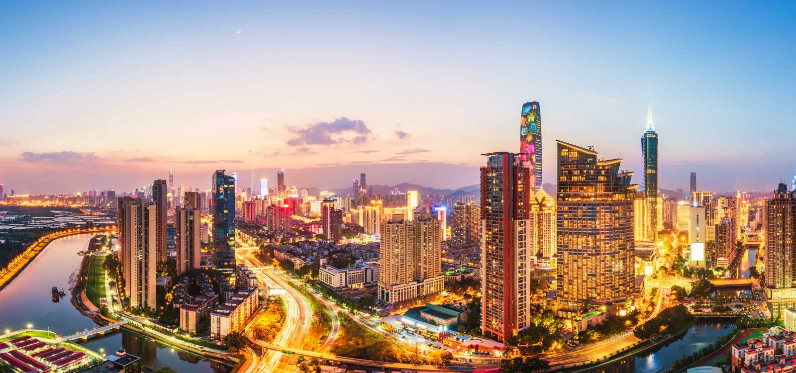 Panoramic view of Shenzhen’s skyline at sunset, with illuminated buildings and traffic-filled roads