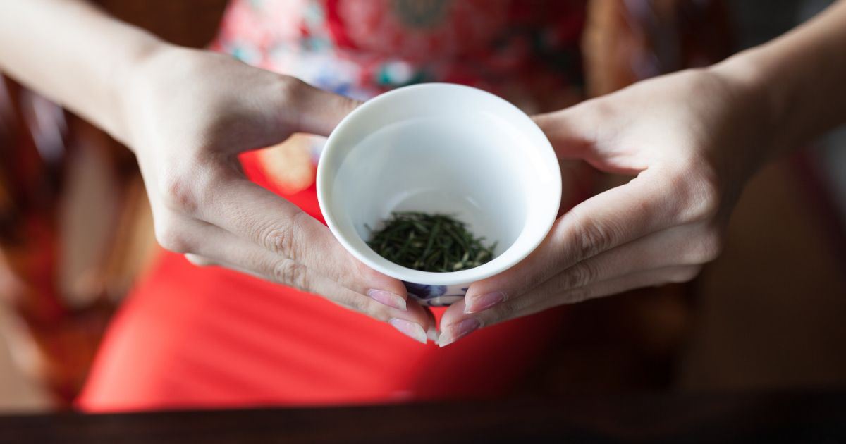 Hojas de té taiwanés junto a una taza de té recién preparado.