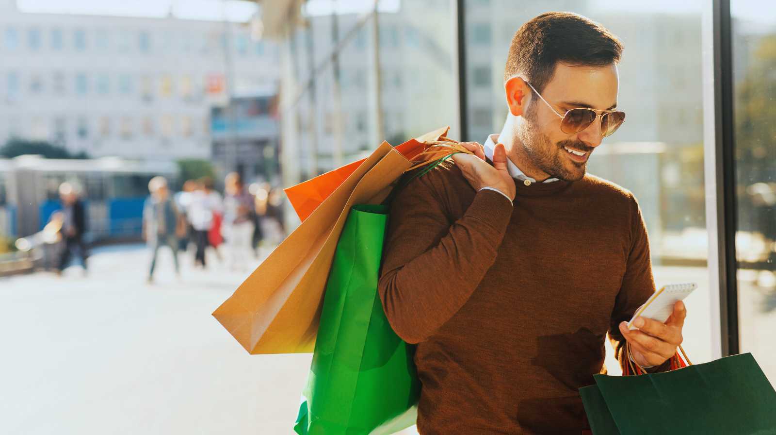 Viajero con bolsas de compras consultando el móvil tras una jornada de compras en China