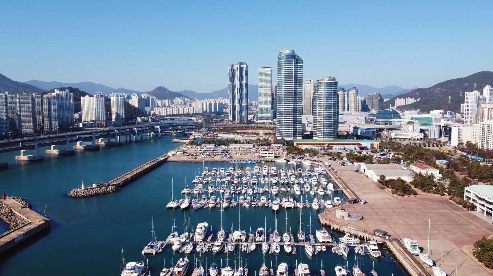 Vista aérea del puerto deportivo de Busan con decenas de yates y rascacielos modernos frente al mar