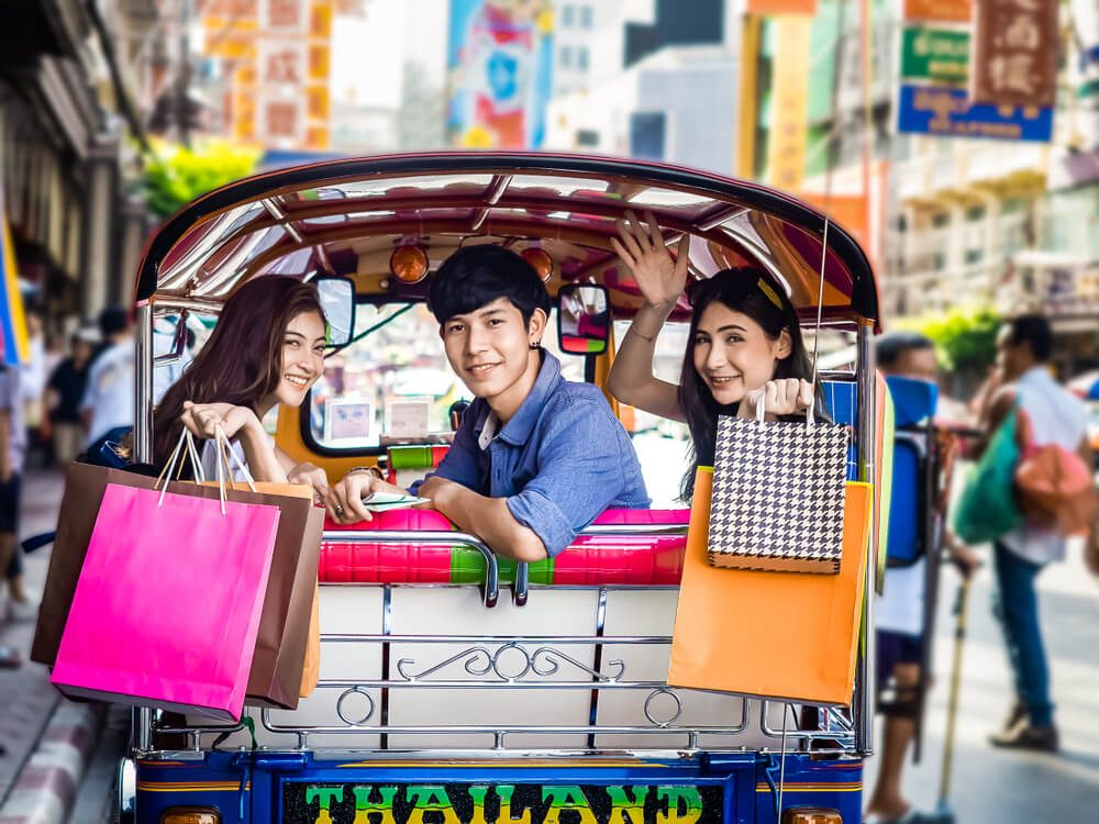 a group of tourist in a tuktuk with a bunch of shopping bags
