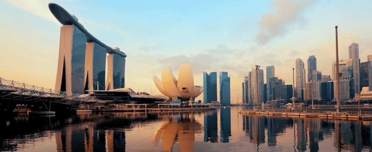 Skyline de Singapour avec le Marina Bay Sands et l'ArtScience Museum se reflétant dans l'eau au coucher du soleil.
