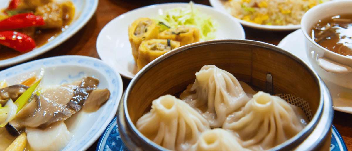 Mesa con platos típicos chinos incluyendo dumplings, sopa y rollitos tradicionales