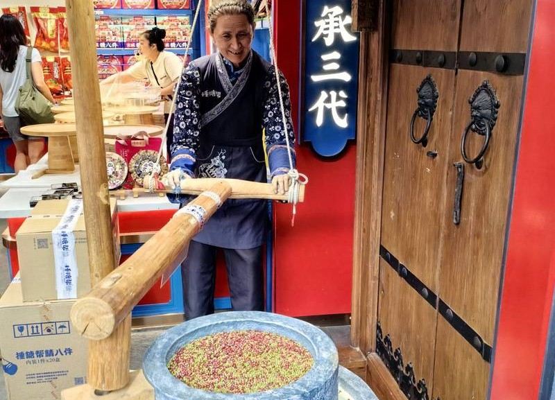 Traditional Chinese snack-making demonstration with a large wooden mallet