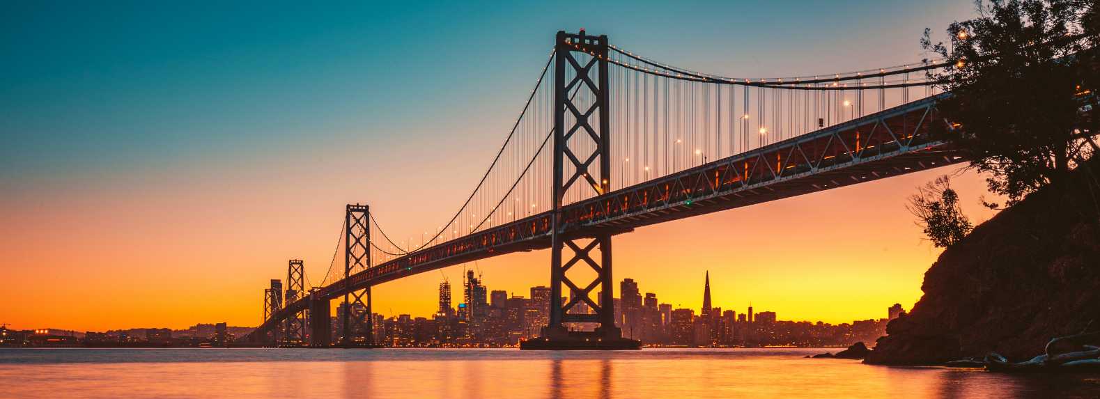 Puente Golden Gate al atardecer con el skyline de San Francisco iluminado al fondo