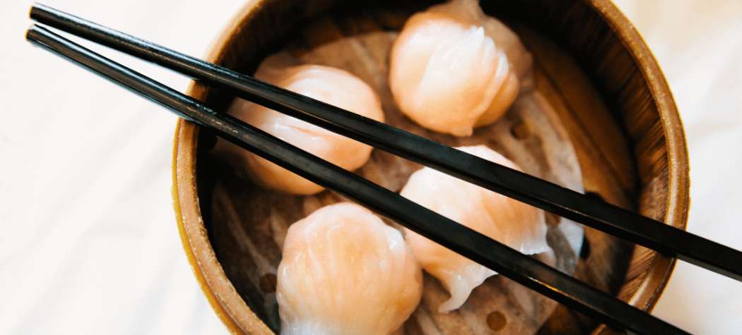 Dim sum tradicional servido en una cesta de bambú con palillos chinos