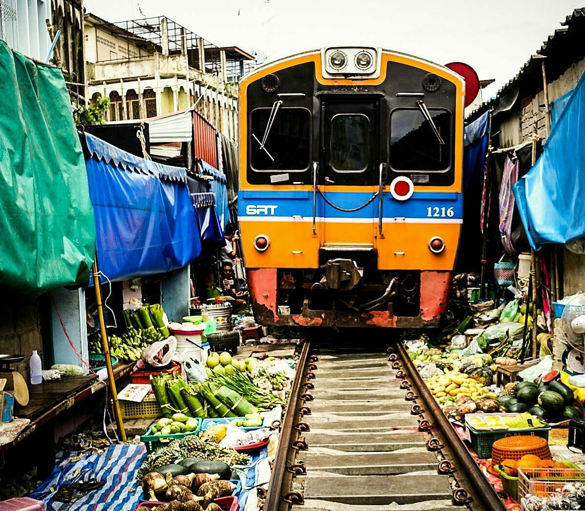 A train going through the market as the vendors keep their wares away from the train tracks