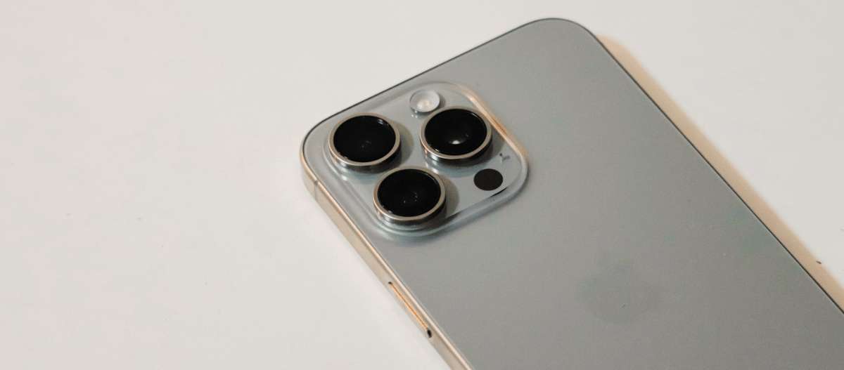 Detail of a smartphone's triple rear camera system on a white surface