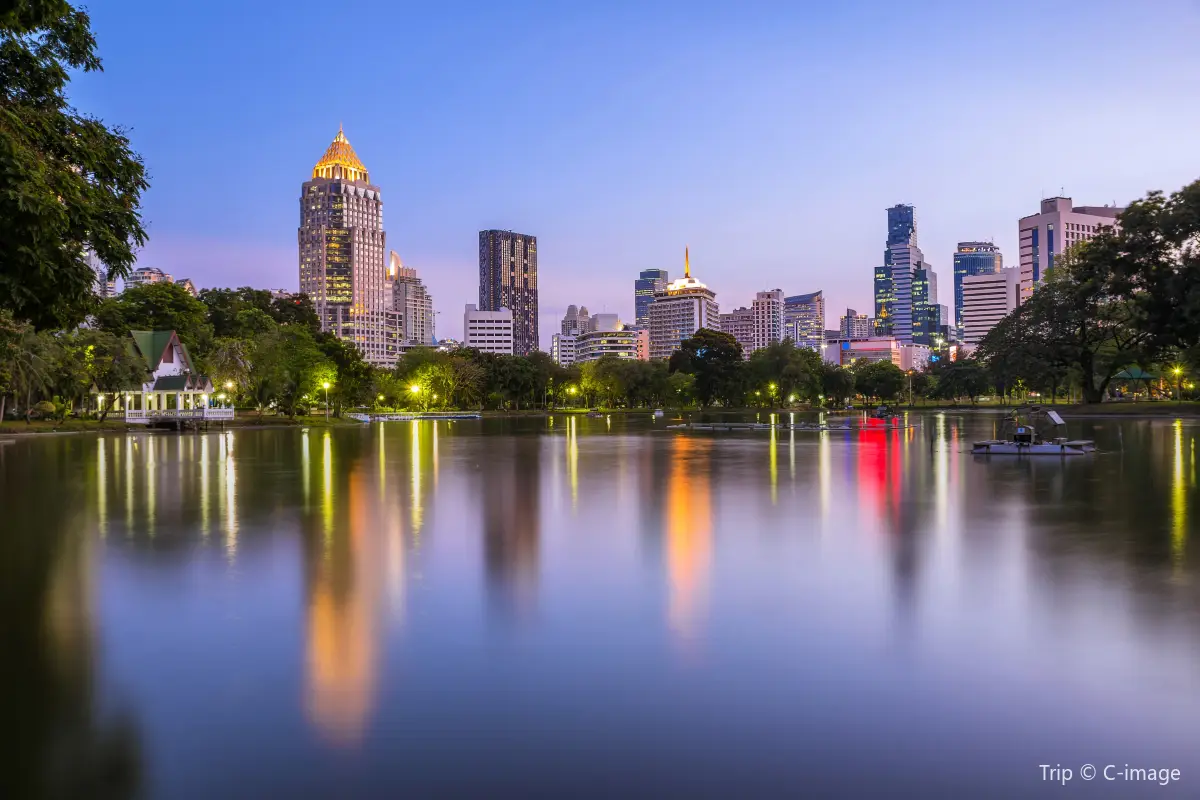 A view of Lumphini Park during evenings, with the lake reflecting the buildings at a perfect angle
