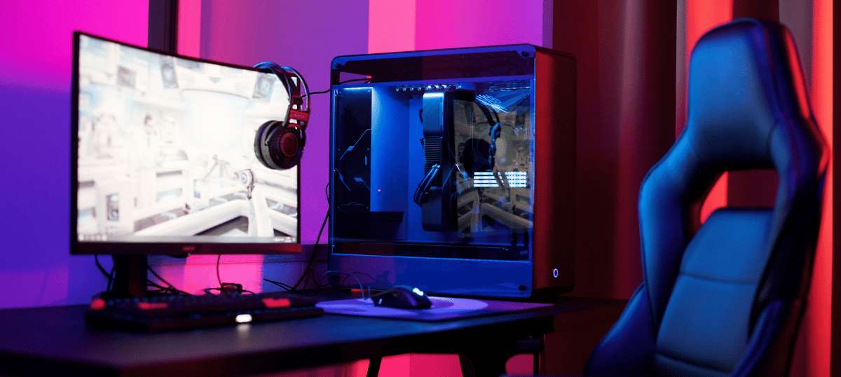 Gamer setup with a curved monitor, PC tower with RGB lighting, and an ergonomic chair under purple and red lights
