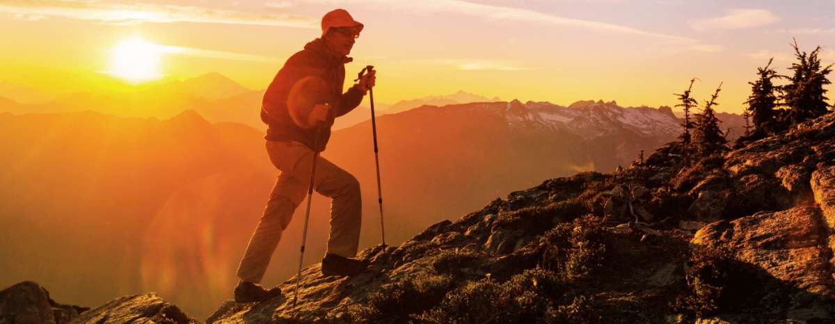 Hiker trekking along a mountain trail at sunset