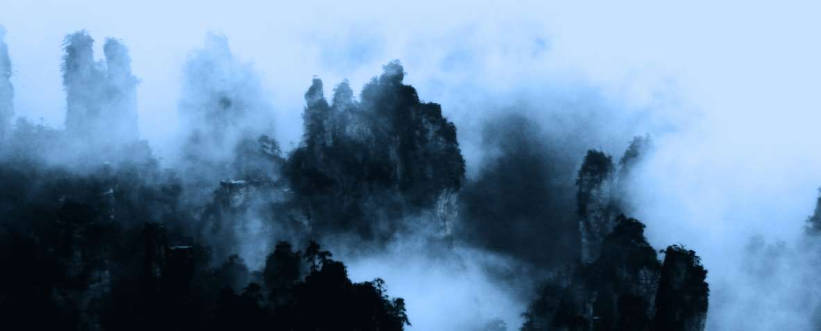 Montañas de Zhangjiajie cubiertas de niebla con picos verticales característicos.