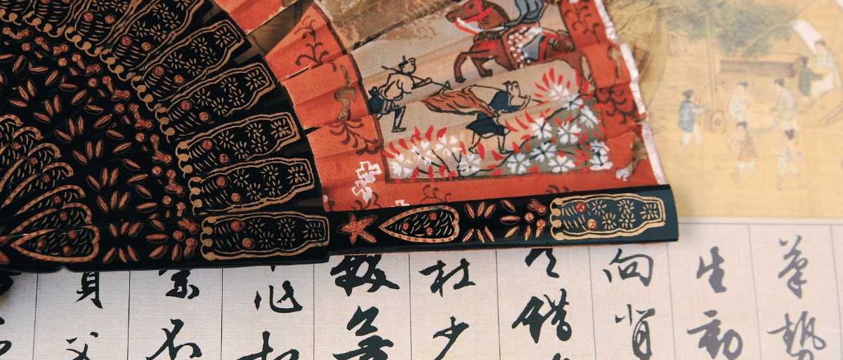 Abanico chino tradicional pintado a mano junto a caligrafía china sobre papel de arroz