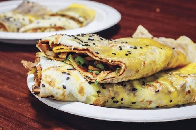 Shanghai-style egg pancake, jidan bing, folded around a savory filling and sprinkled with black sesame seeds