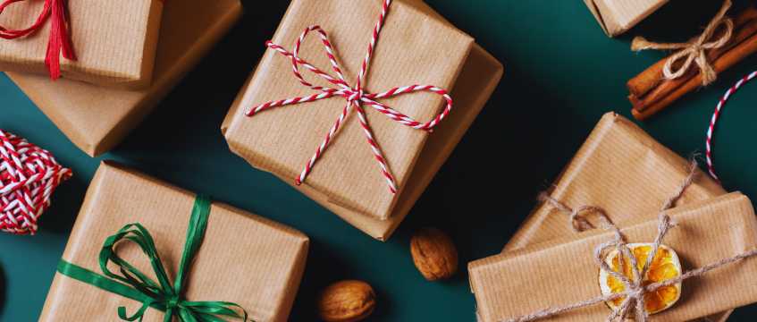 Pacchetti regalo avvolti in carta kraft con spago decorativo su uno sfondo scuro