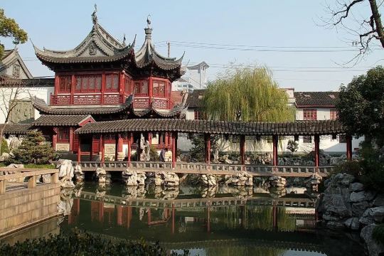 Traditional Chinese pavilion and covered walkway reflected in a pond at a Shanghai garden