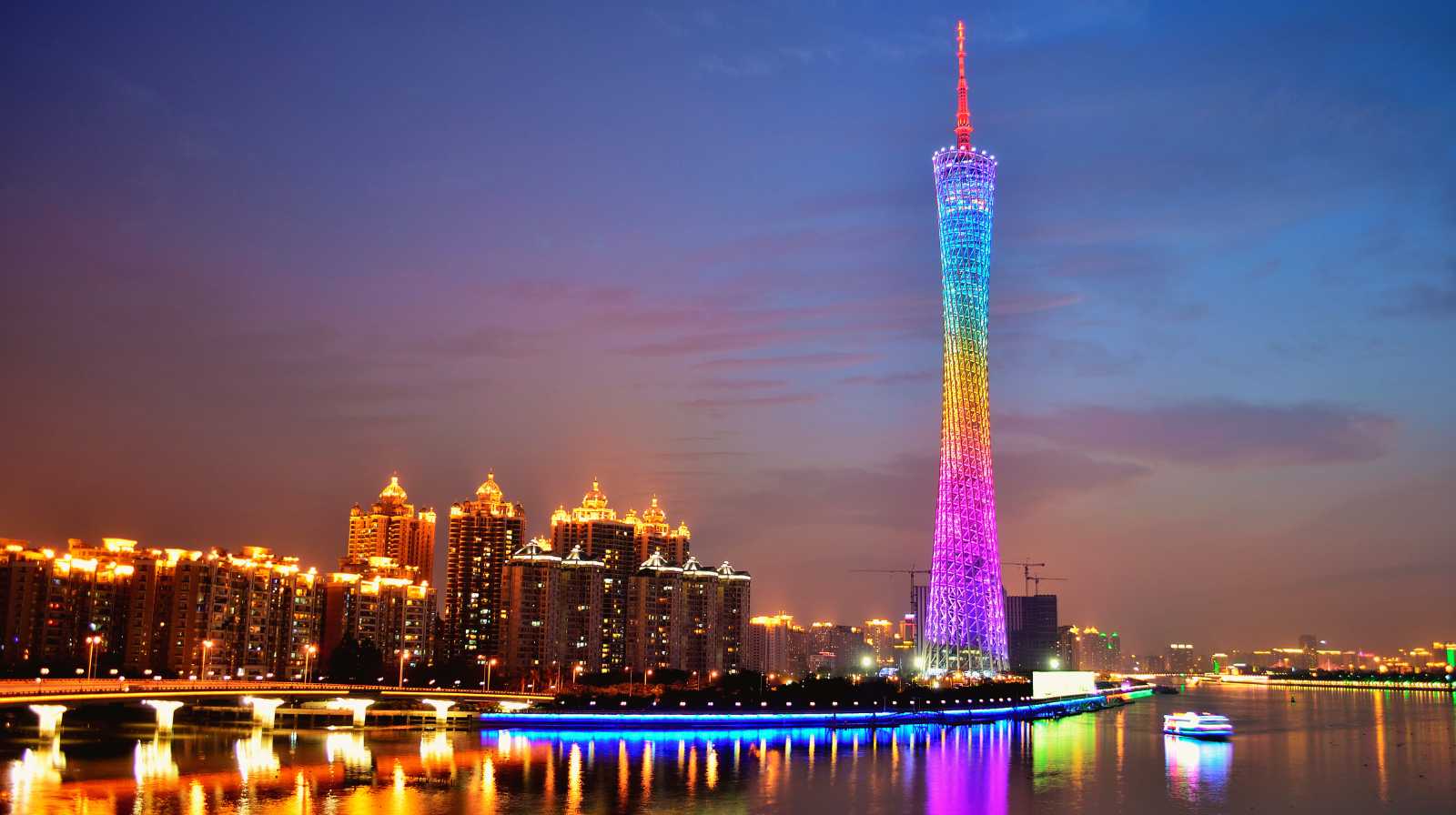 Torre de Cantón iluminada con luces de colores reflejadas en el río durante la noche