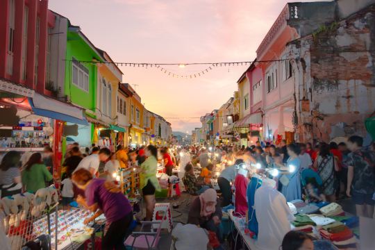 Phuket Old Town walking street market at dusk, pastel shophouses on both sides